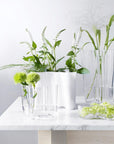 Photo de présentation du célèbre vase Alvar Aalto sur une table en marbre blanc et des fleurs