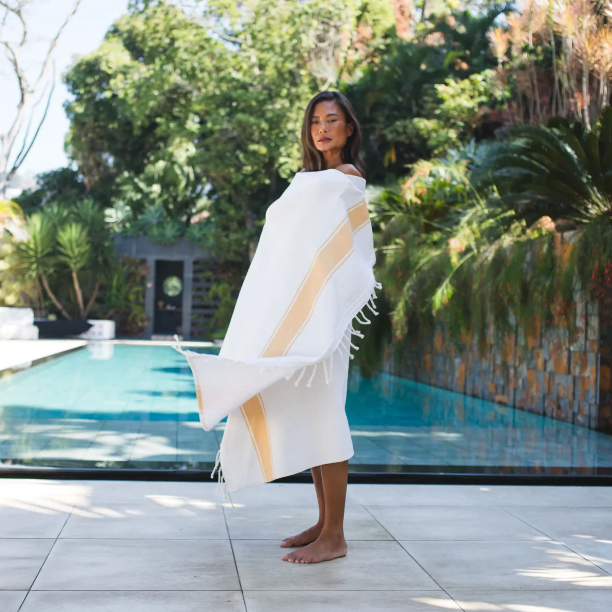 Fouta éponge jaune moutarde portée sur mannequin devant piscine