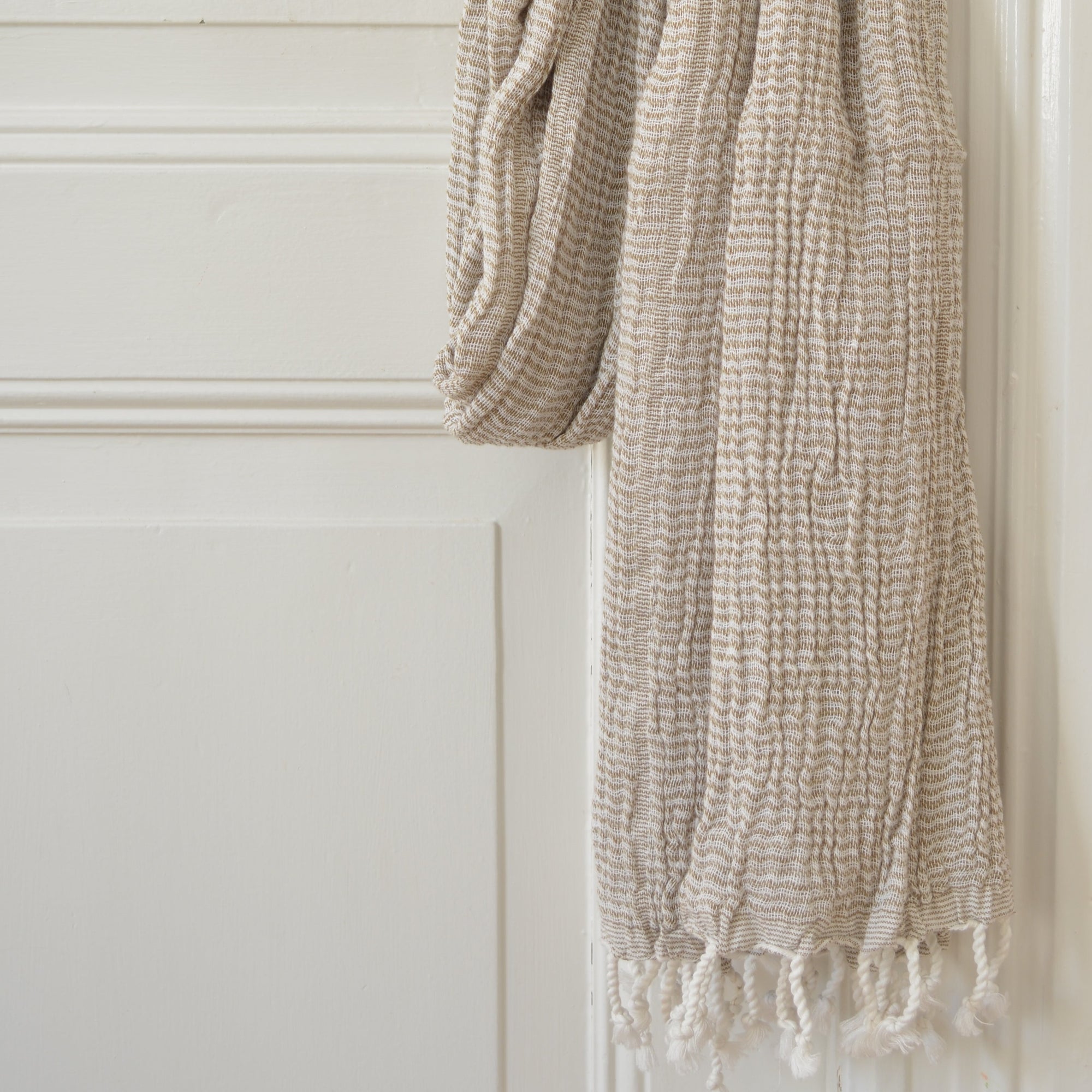 Serviette fouta couleur vert olive pendue à une poignet de porte 