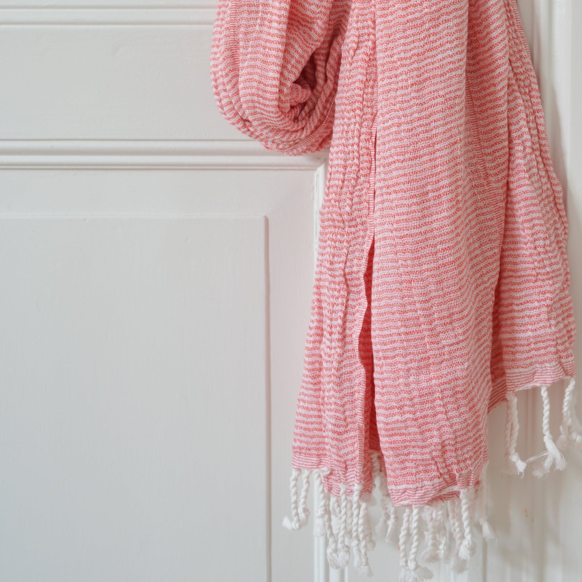Serviette fouta couleur rouge brique pendue à une poignet de porte 