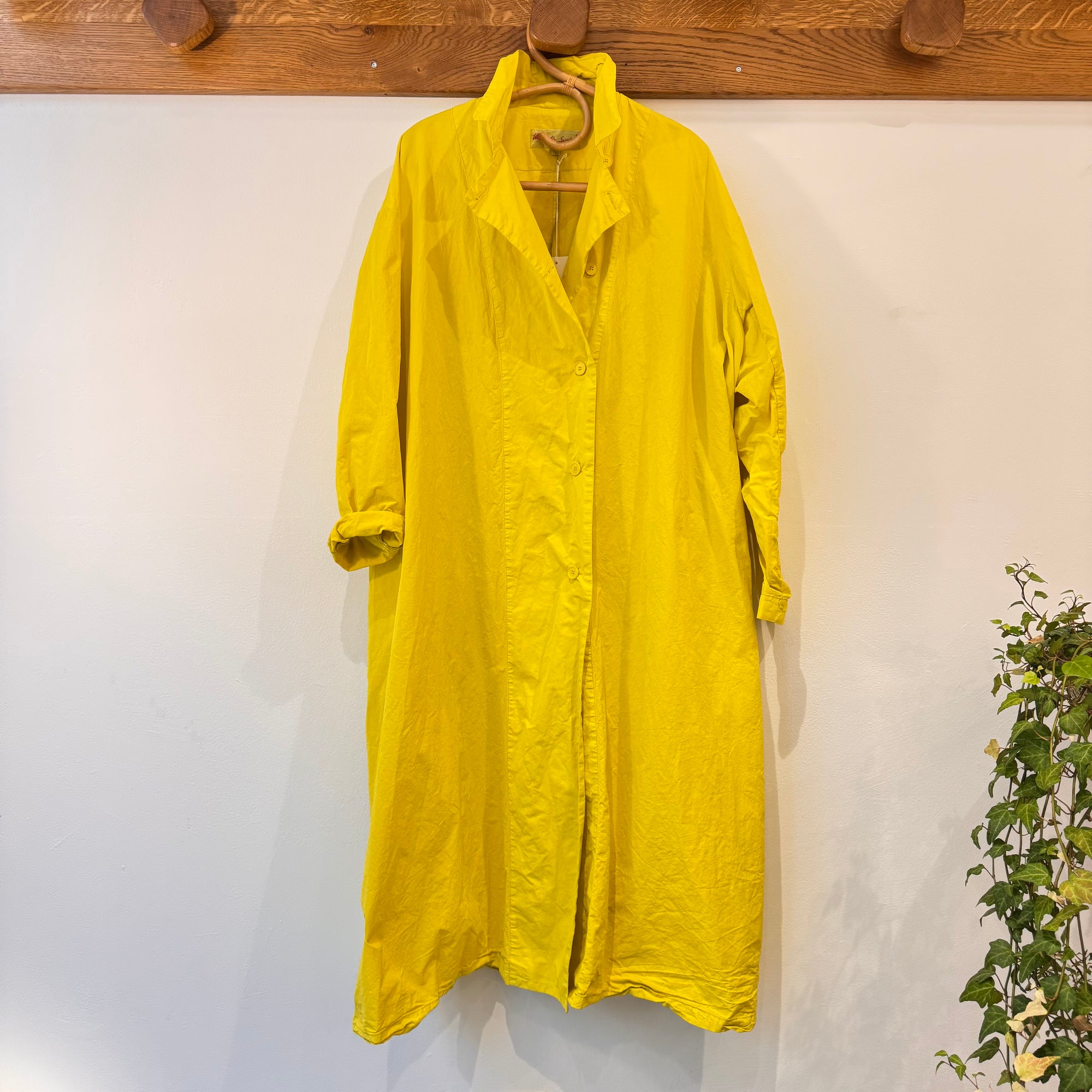 Trench neon accroché au porte manteau par un ceintre