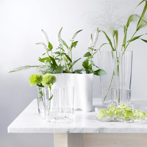 Photo de présentation du célèbre vase Alvar Aalto sur une table en marbre blanc et des fleurs